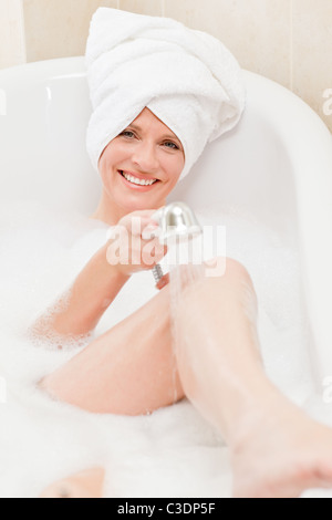 Smiling woman taking a bath with a towel on her head Stock Photo