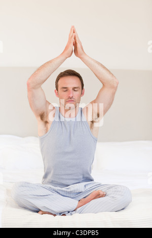 Man practicing yoga on his bed Stock Photo