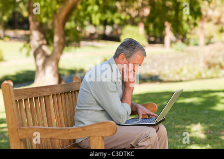 Elderly man working on his laptop in the park Stock Photo