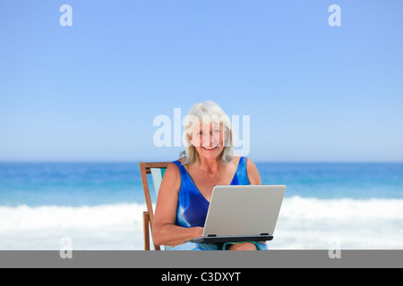 Woman working on her laptop on the beach Stock Photo