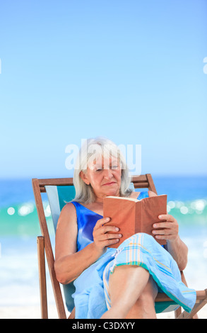 Senior woman reading a book on the beach Stock Photo