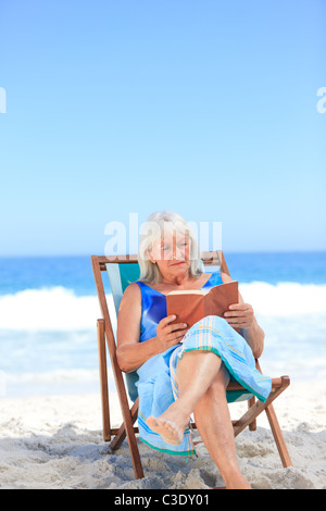 Senior woman reading a book on the beach Stock Photo