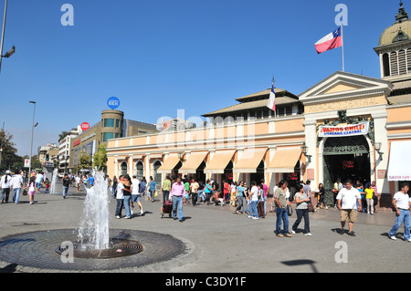 Blue sky view of pavement fountain and many people walking in front of the salmon pink Mercado Central building, Santiago, Chile Stock Photo