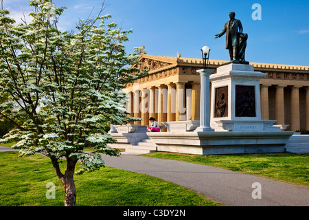 Young Woman relaxing below statue of JW Thomas and Parthenon replica in Centennial Park, Nashville, Tennessee, USA Stock Photo