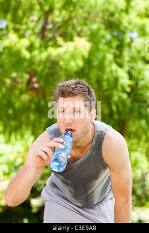 Sporty man drinking water in the park Stock Photo - Alamy