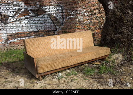 Aged abandoned folding sofa in the city suburbs Stock Photo