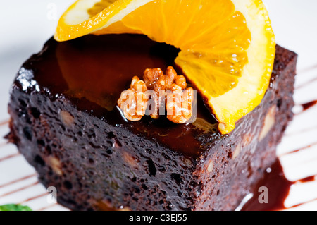 fresh baked delicious chocolate and walnuts cake with slice of orance on top Stock Photo