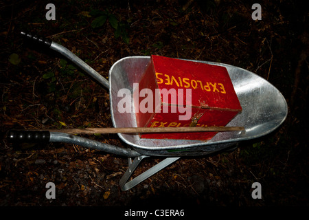 Barrow with red wooden box full of explosives in dark forest. Stock Photo