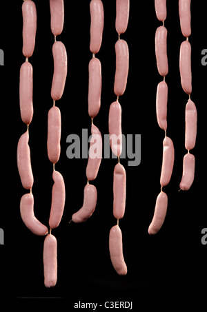 Bunches of freshly prepared raw sausages hanging isolated on black background Stock Photo
