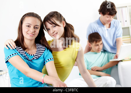 Two teenage girls looking at camera and smiling against their boyfriends Stock Photo
