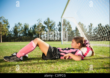 Hispanic girl soccer player laying with head on soccer ball Stock Photo