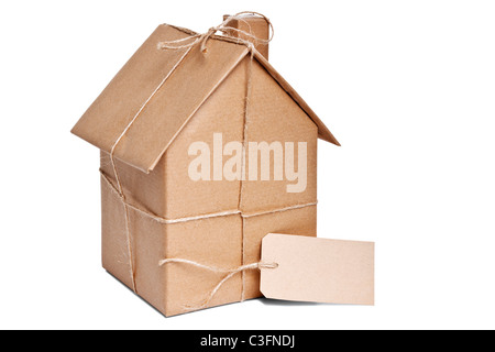 Photo of a wrapped house in brown recycled paper with label, cut out on a white background. Stock Photo