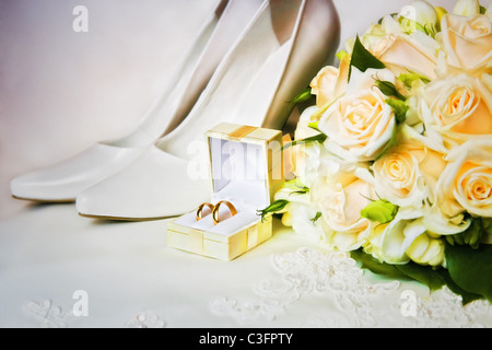 wedding rings in box with bouquet from roses and high heel shoes Stock Photo