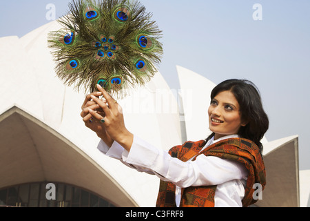 Mixed race woman holding peacock feather fan Stock Photo