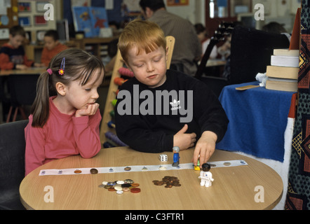 Two children in primary school working with pennies and buttons learning to add and subtract Stock Photo