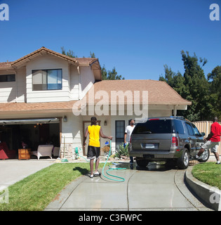Black family washing car in driveway