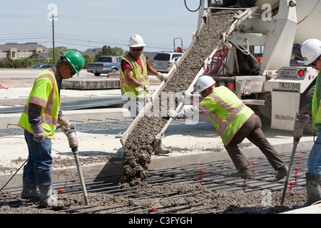 Male highway construction workers pour fresh concrete along new stretch of highway in Texas Stock Photo