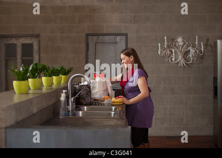 Pregnant Caucasian woman with groceries in kitchen Stock Photo