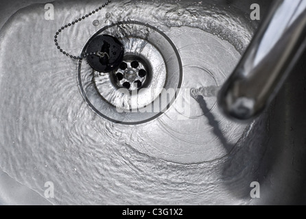 Running Water Draining Down the Plughole in Kitchen Sink Stock Photo