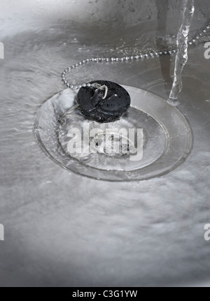 Water Running Down the Plughole in Kitchen Sink Stock Photo
