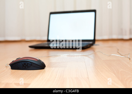 Opened laptop and a computer mouse on the floor of the room Stock Photo