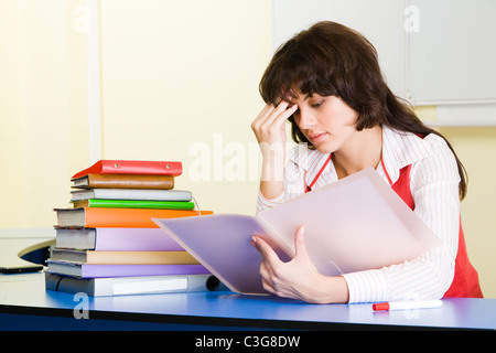 Photo of pensive teacher sitting at the desk and refreshing study material before lesson Stock Photo