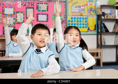 Students raising hands in the classroom Stock Photo