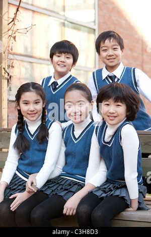 Five students sitting together on a bench Stock Photo