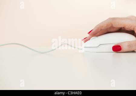 Close up of woman's hand with red nail polish holding computer mouse Stock Photo