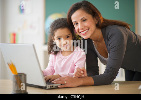 Girl (6-7) with female teacher using laptop in classroom Stock Photo ...