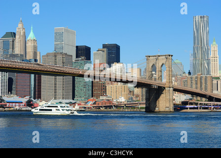 A river cruise boat on the East River heading under the Brooklyn Bridge in New York City.