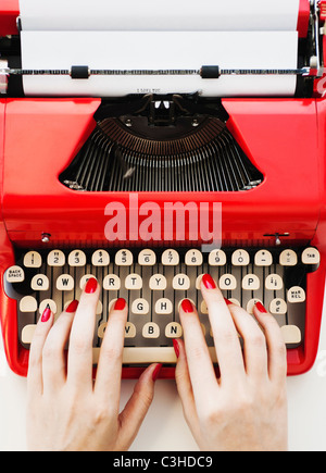 Close up of woman's hands with red nail polish typing on antique typewriter Stock Photo