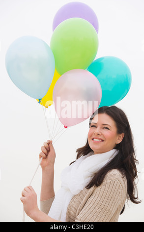 Young woman holding bunch of balloons smiling Stock Photo