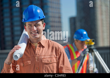 Portrait of construction worker holding rolled up blueprint Stock Photo