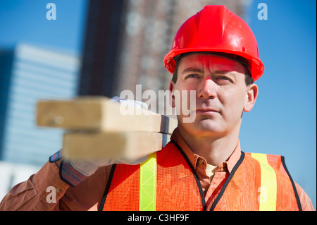 Construction worker carrying planks Stock Photo