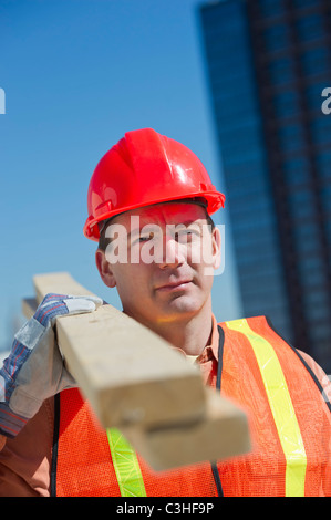 Construction worker carrying planks Stock Photo