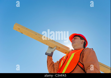 Construction worker carrying planks Stock Photo