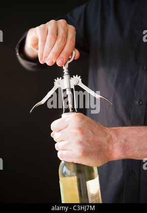 Man opening wine bottle, close-up of hands Stock Photo