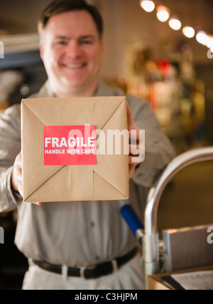 Delivery man holding box with fragile sign Stock Photo