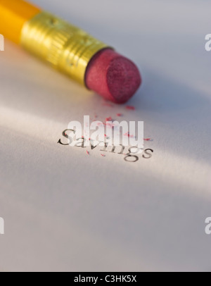 Studio shot of pencil erasing the word savings from piece of paper Stock Photo