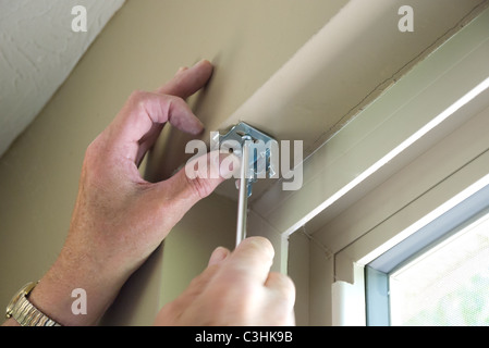 Hands installing blind hardware onto window frame Stock Photo