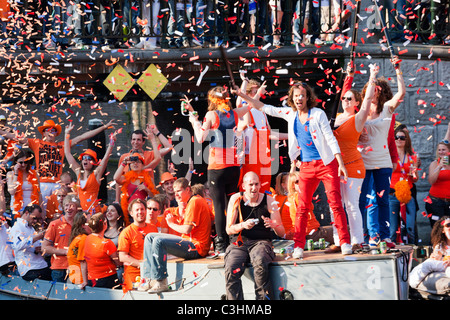 King's Day, the King's birthday, formerly Queen's day. Amsterdam Canal Parade Boats people partying shooting orange confetti. Stock Photo