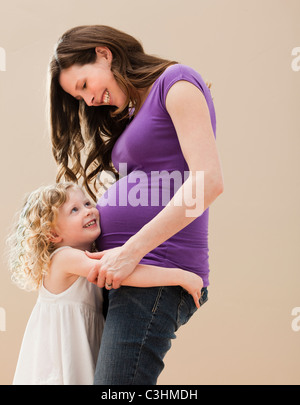 Portrait of girl (2-3) and pregnant mother embracing Stock Photo