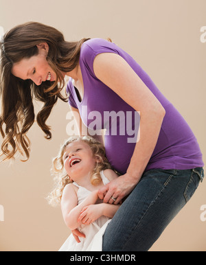 Portrait of girl (2-3) and pregnant mother embracing Stock Photo