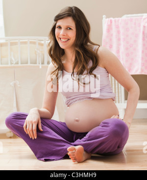 Young pregnant woman sitting on ground Stock Photo