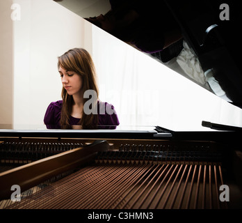 Young woman playing grand piano Stock Photo