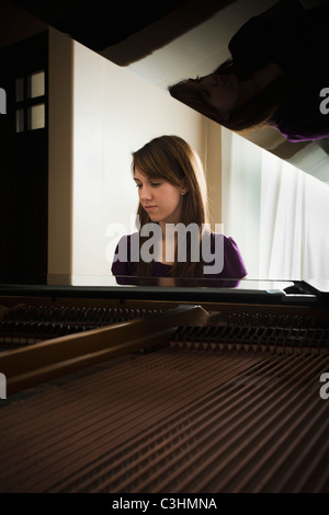 Young woman playing grand piano Stock Photo
