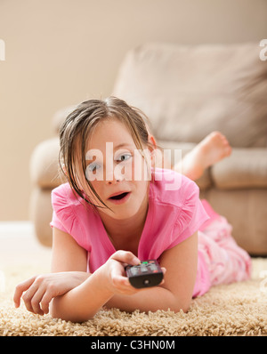 Portrait of girl (10-11) lying on floor holding remote control Stock Photo