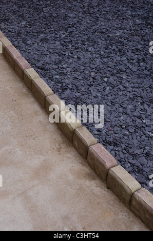 Chipped slate covered ground beside a garden path Stock Photo