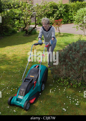 OLDER WOMAN MOWING LAWN WITH ELECTRIC MOWER UK Stock Photo - Alamy